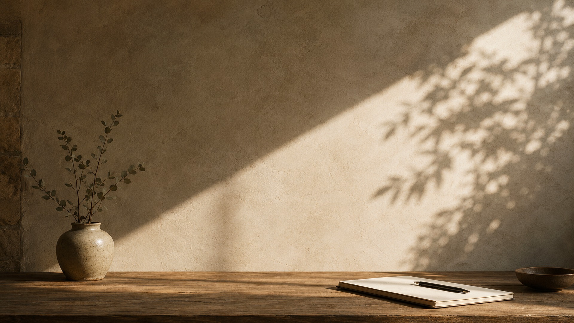 A ceramic vase with delicate branches on a wooden table in warm window light