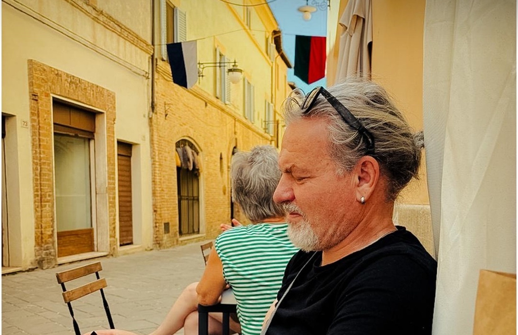 Rob seated at a street café, looking at the camera in his hands