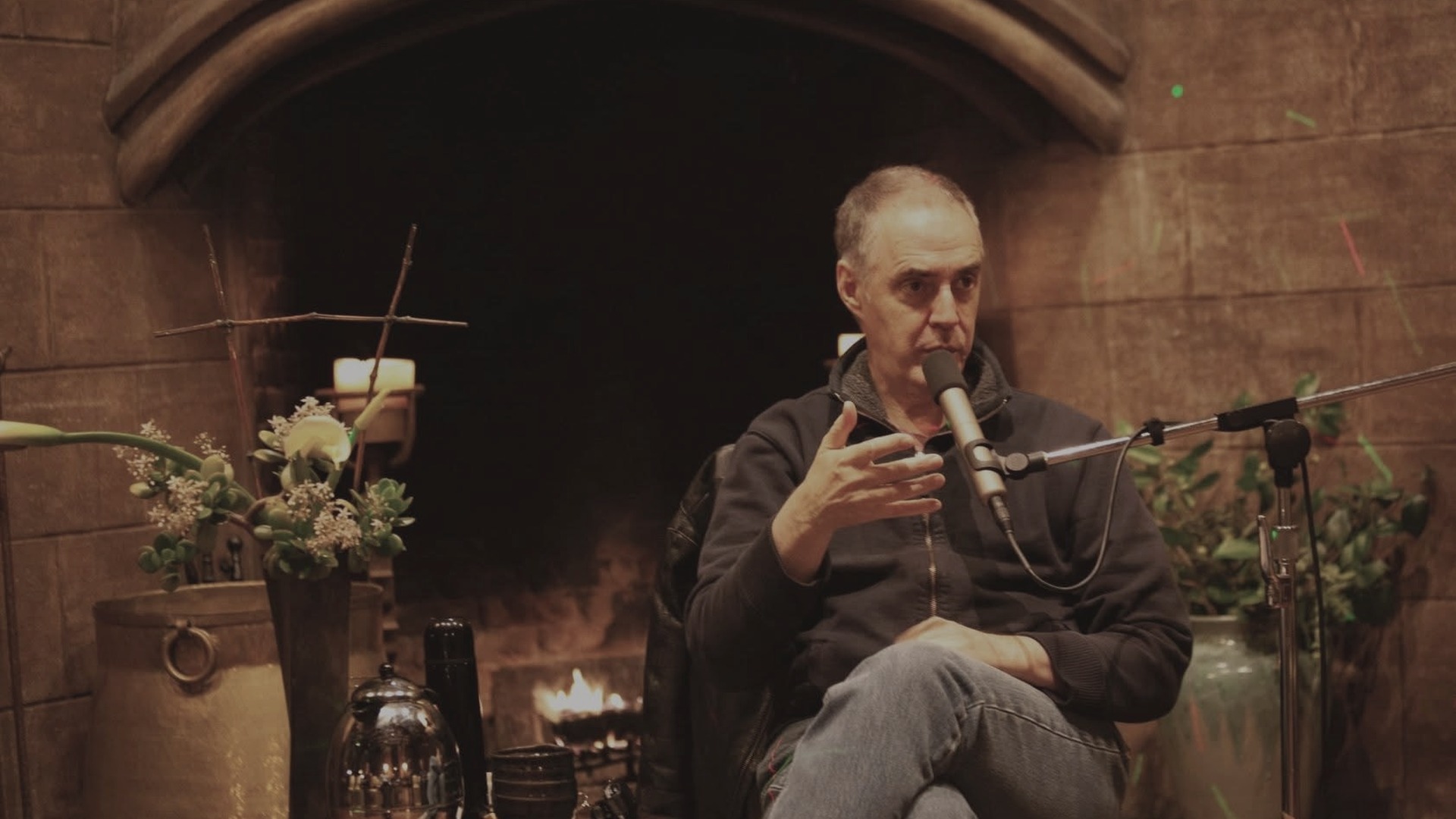 Peter Brown speaking beside a fireplace