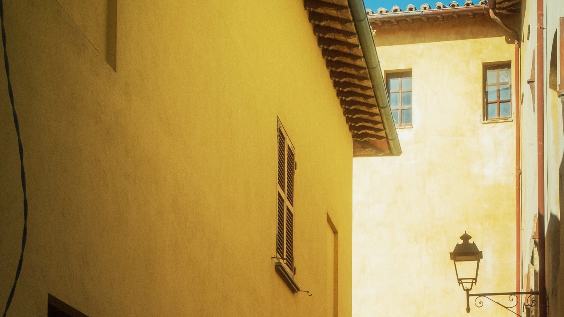 A narrow sunlit street between warm ochre buildings